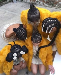Group of 5 Black women crouched, showing their braided hair