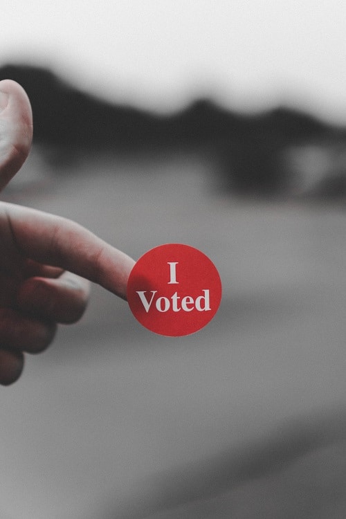 A red "I voted" sticker on someone's finger