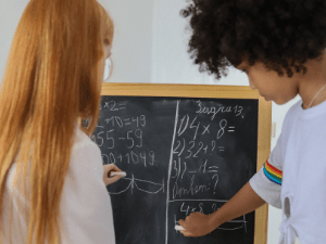 Two girls writing on blackboard