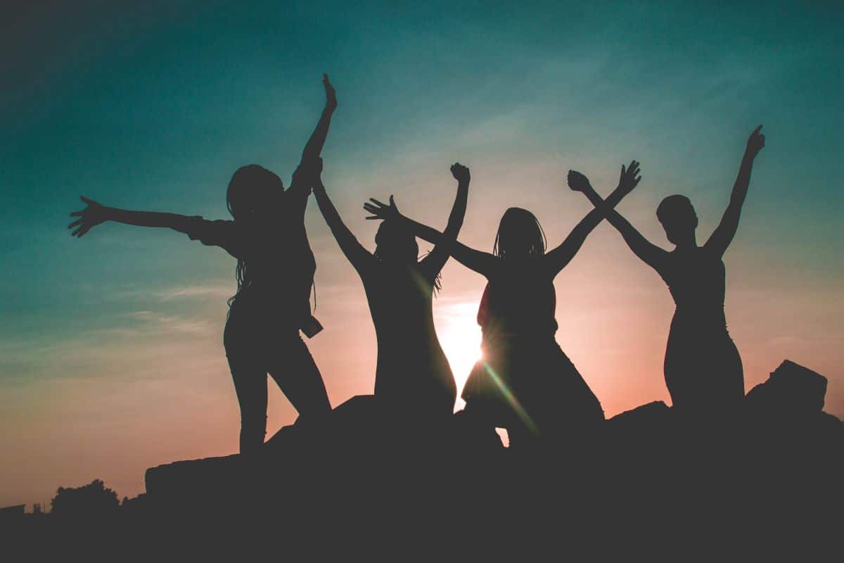 Girls with arms in the air, enjoying a sunset