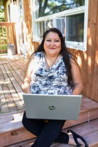 Woman sitting on an outdoor deck with a laptop computer